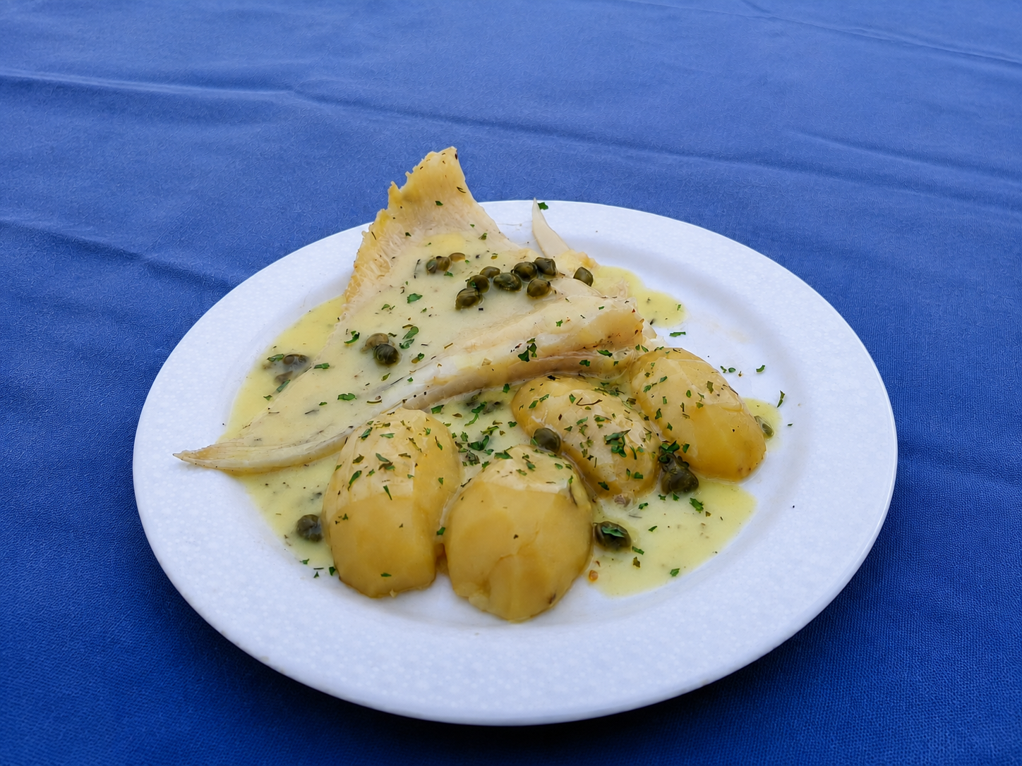 Aile de raie cuisinée avec pommes de terre, sauce et câpres